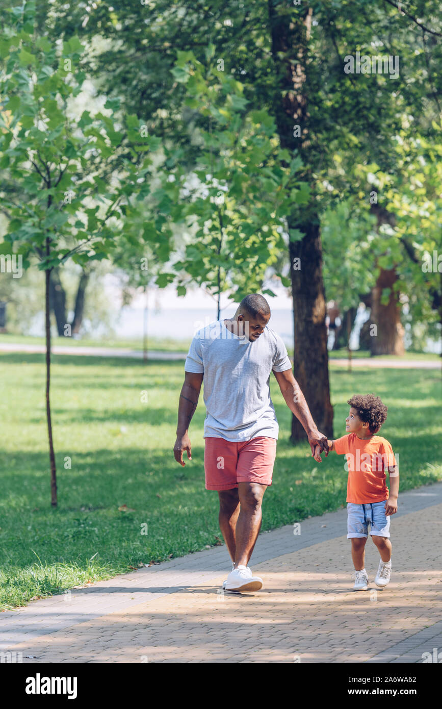 african american father and son holding hands and looking at each other ...