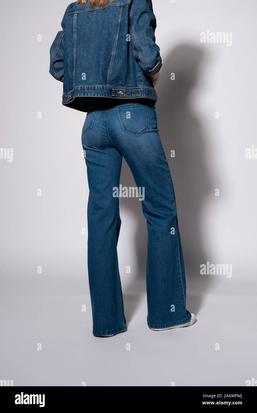 cropped view of young woman in denim jeans and jacket standing on white Stock Photo
