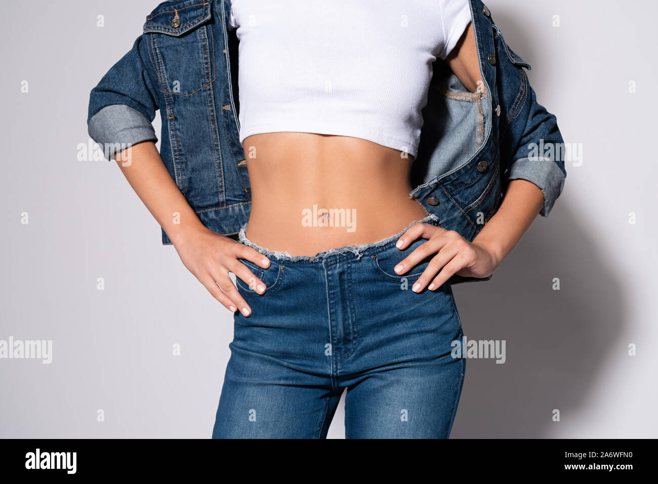 cropped view of woman in jeans standing with hands on hips on white Stock Photo