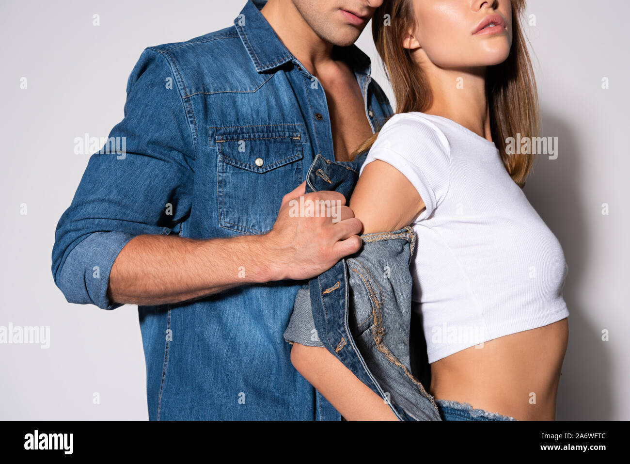cropped view of man taking off denim jacket of girl on white Stock Photo