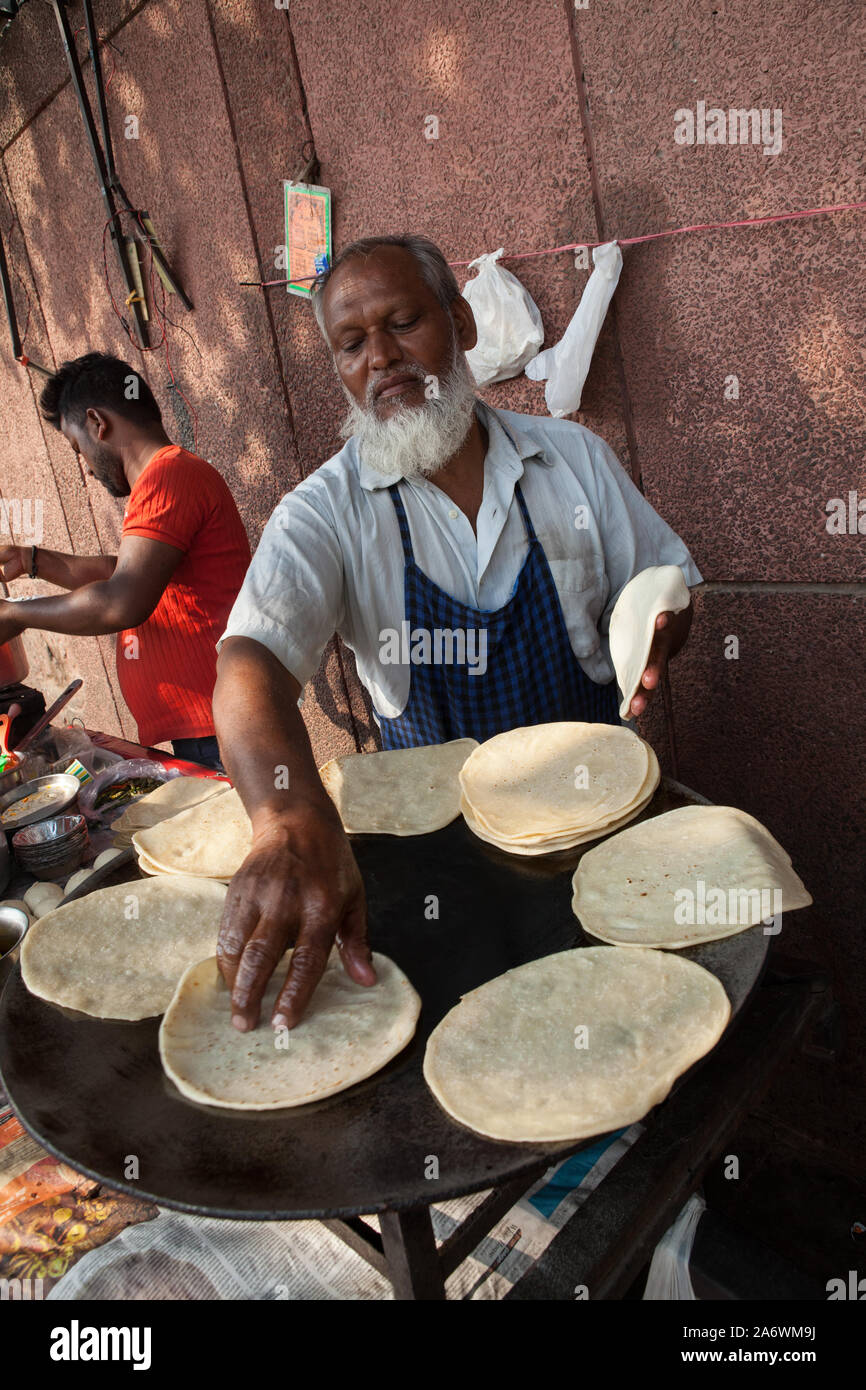 A street vendor cooks chapatis at his food stall in the old city of Delhi Stock Photo