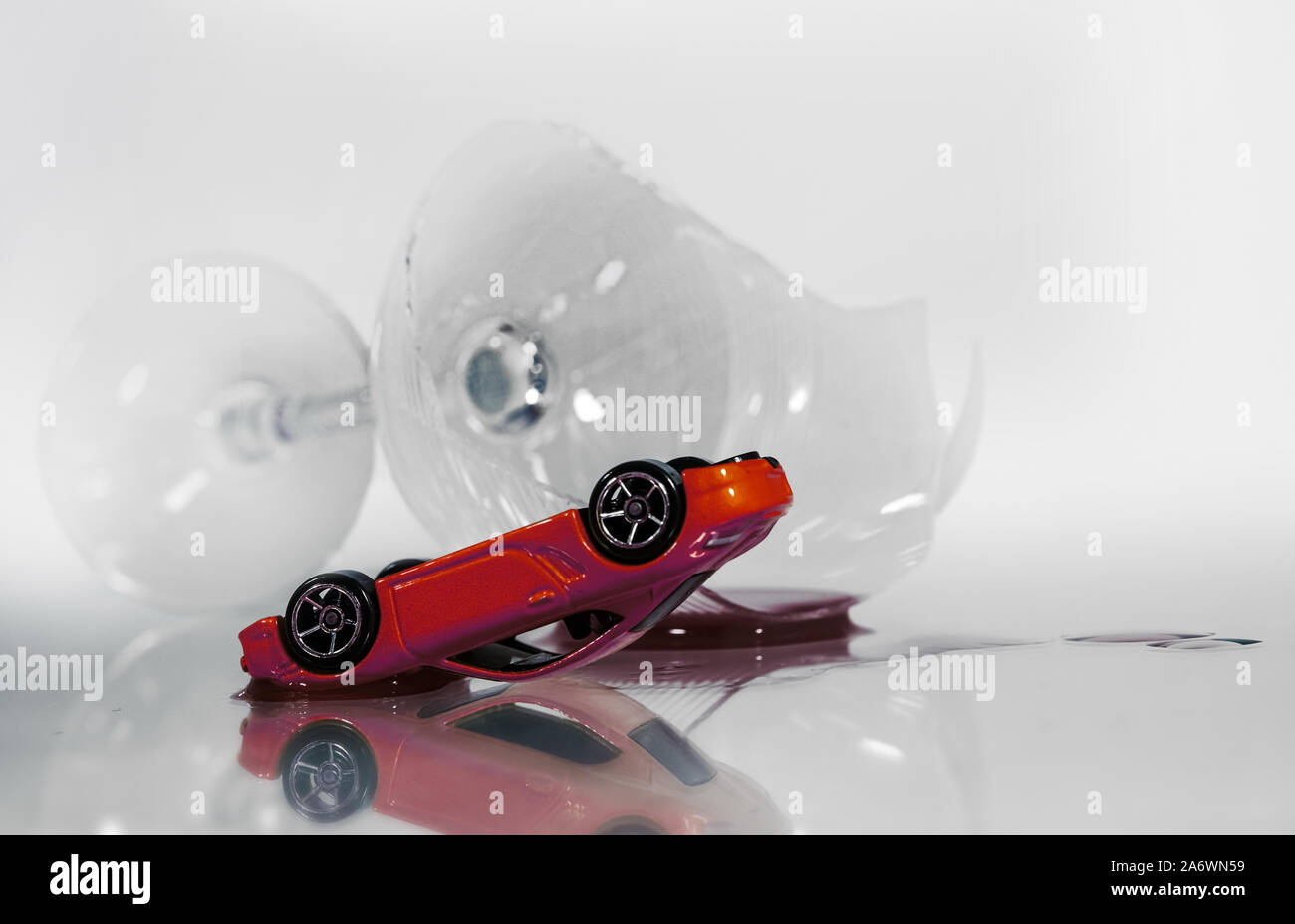 A toppled toy car next to a broken wine glass. High key. Stock Photo