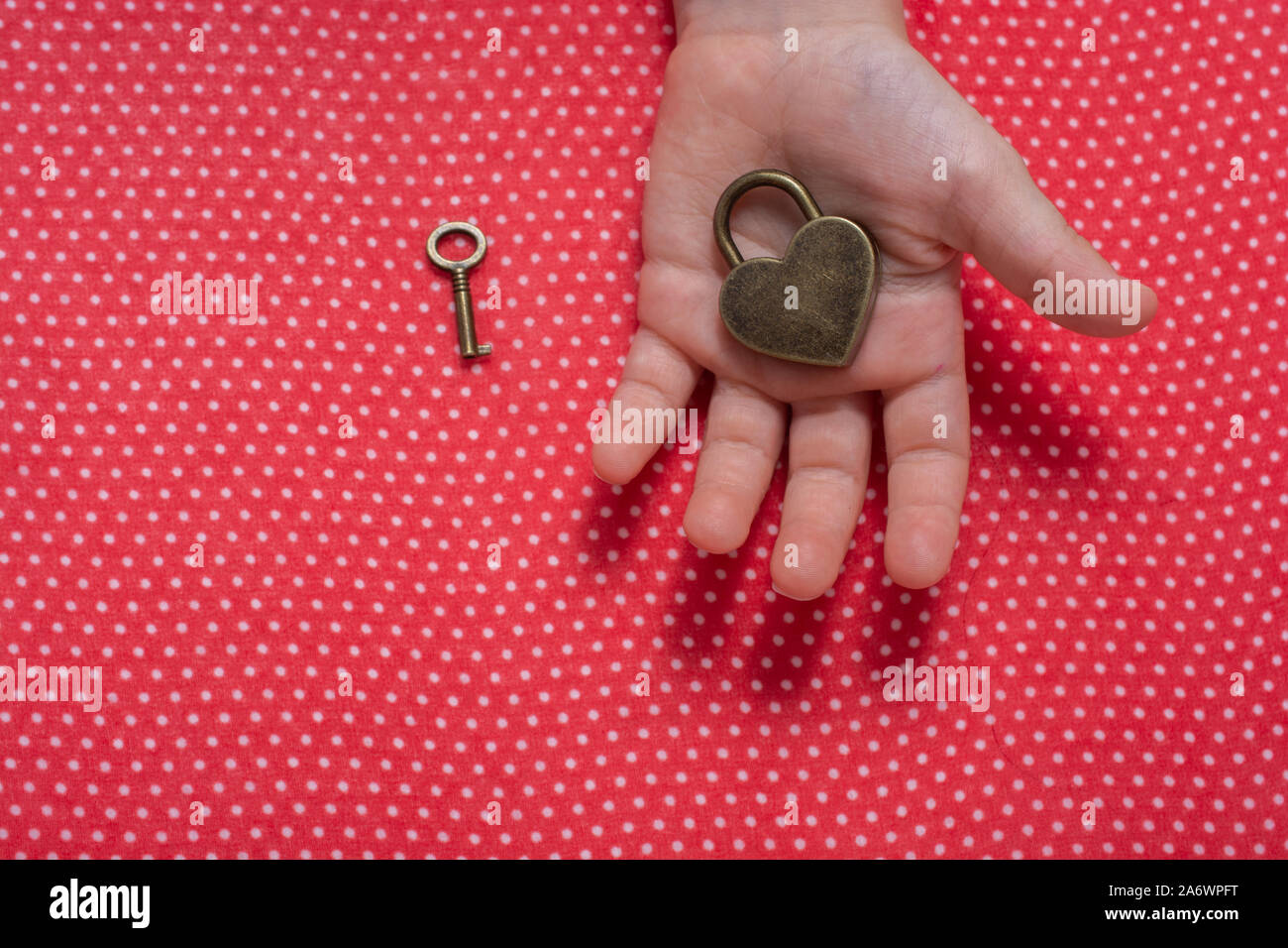 Hand holding a heart shaped lock and key on a red background Stock ...