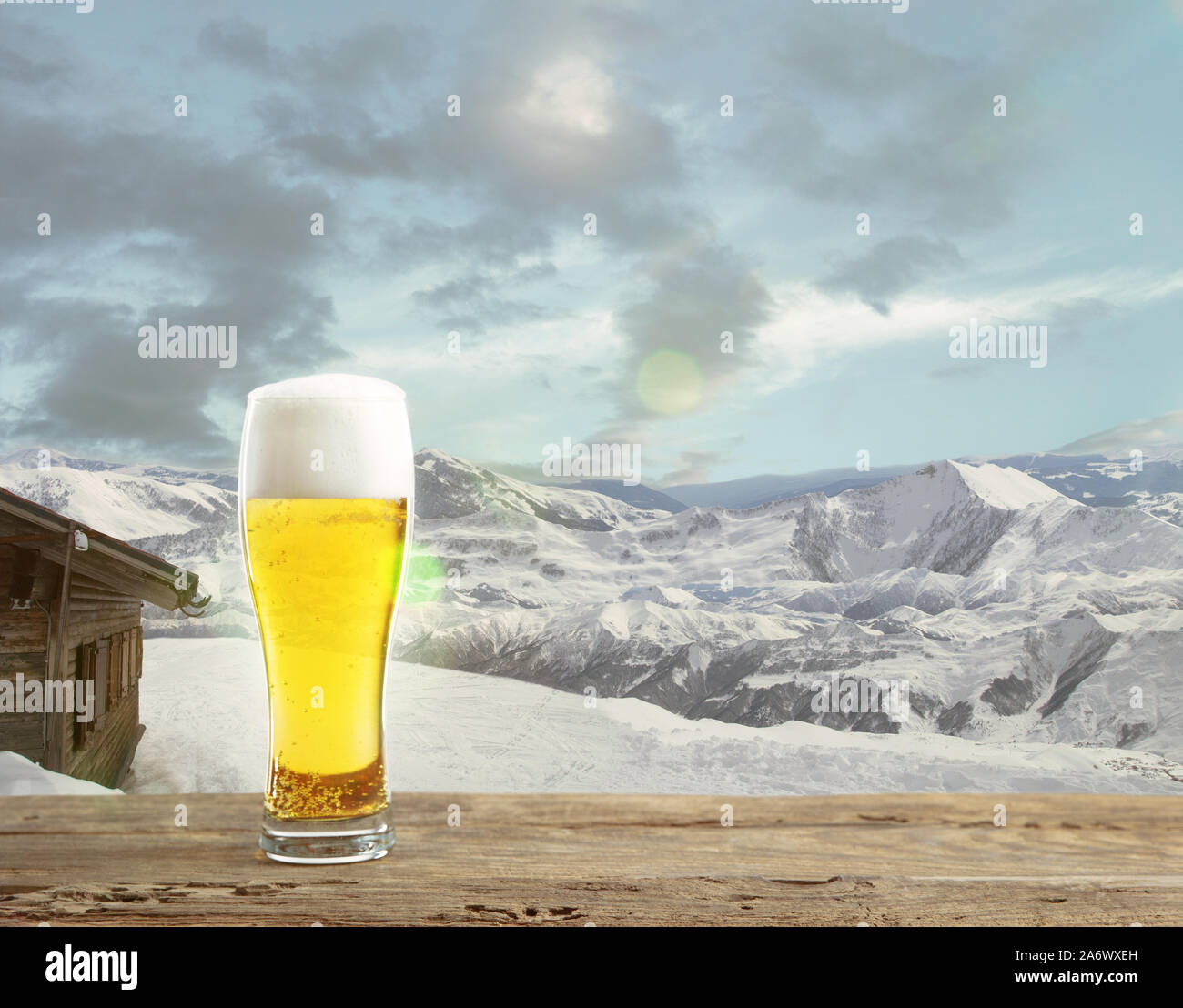 Single light beer in glass and landscape of mountains on background. Alcohole drink and sunshine look and clear sky in front of it. Warm in spring day, holidays, travel, adventure time. Stock Photo