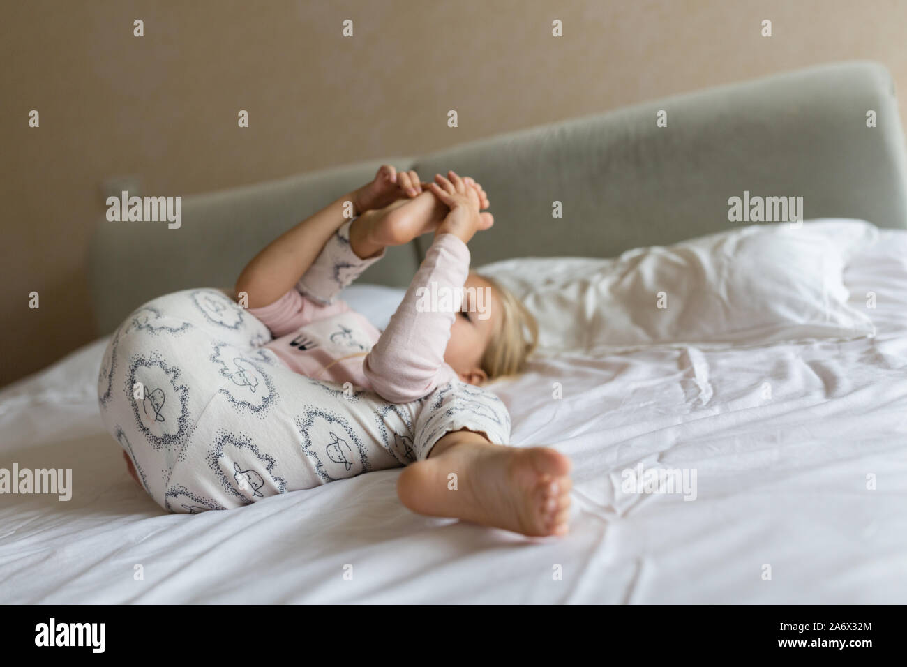 Cute blonde little girl in pajamas playing in white bed early morning before going to kindergarten. Bedtime playtime relaxation concept Stock Photo Alamy