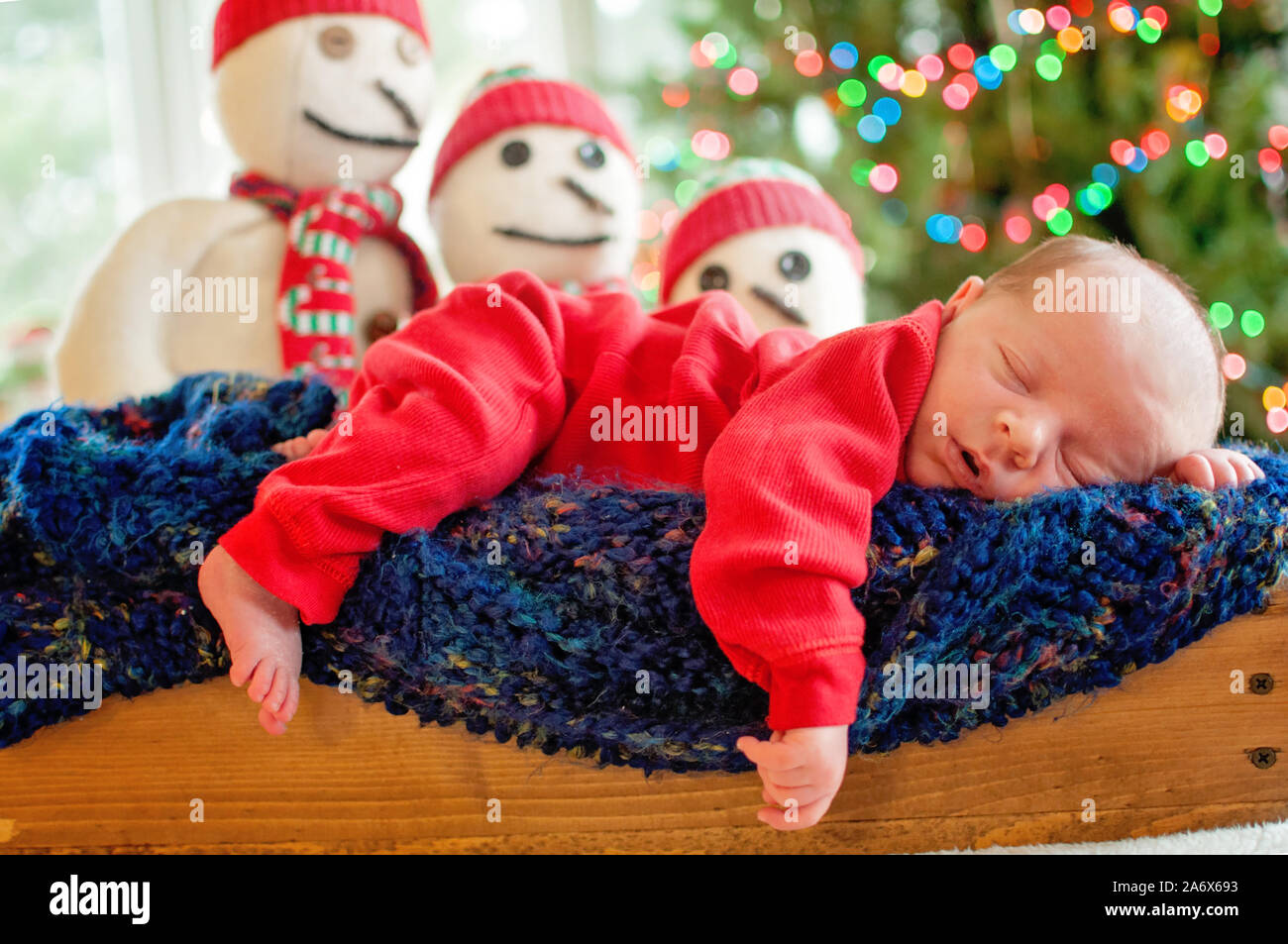 newborn baby laying in wooden manger on top of a blue knitted afghan Stock Photo