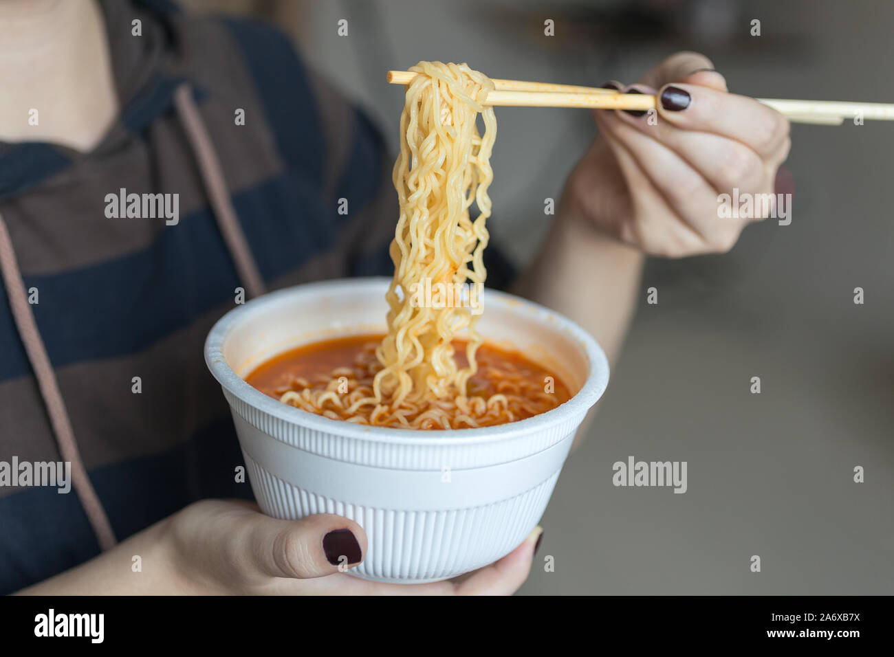 Bowl of instant noodles ramen in hands with chopsticks, close up Stock Photo