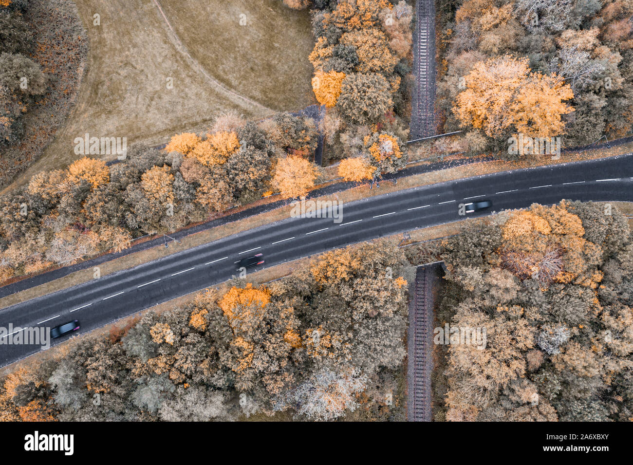 Top down drone shoot over asphalt road junction over railroad tracks on autumnal evening in United Kingdom Stock Photo