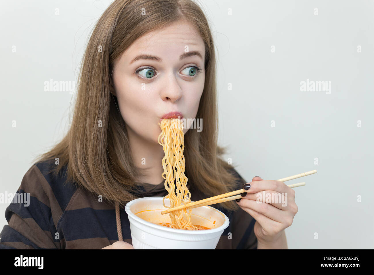 Young caucasian girl woman eating instant noodles ramen with chopsticks