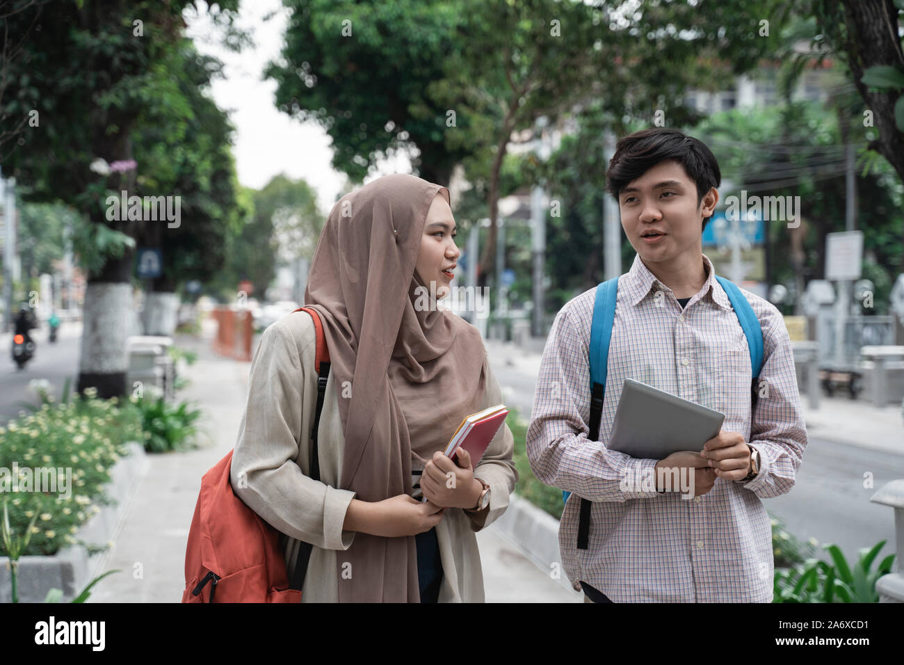 male and female student holding tablet and books walking Stock Photo ...