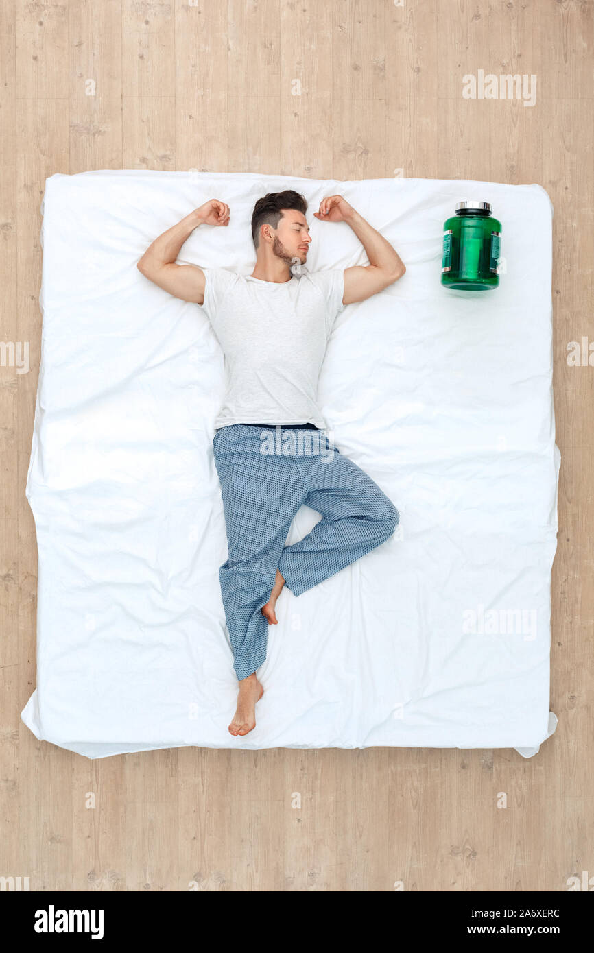 Bedtime. Guy sleeping peaceful on bed top view with bodybuilding
