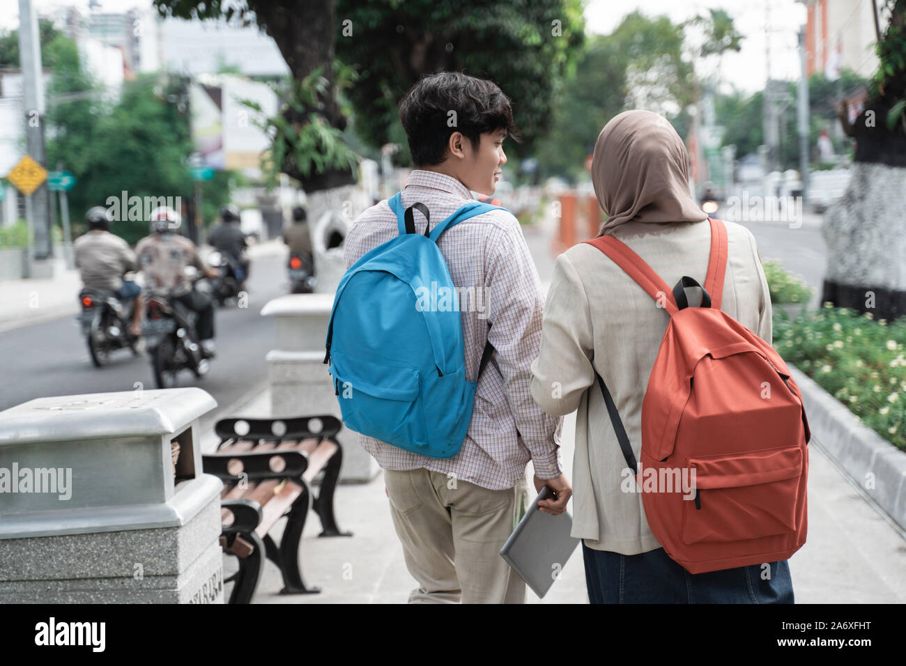 two teenage student smiling walk away while looking back Stock Photo