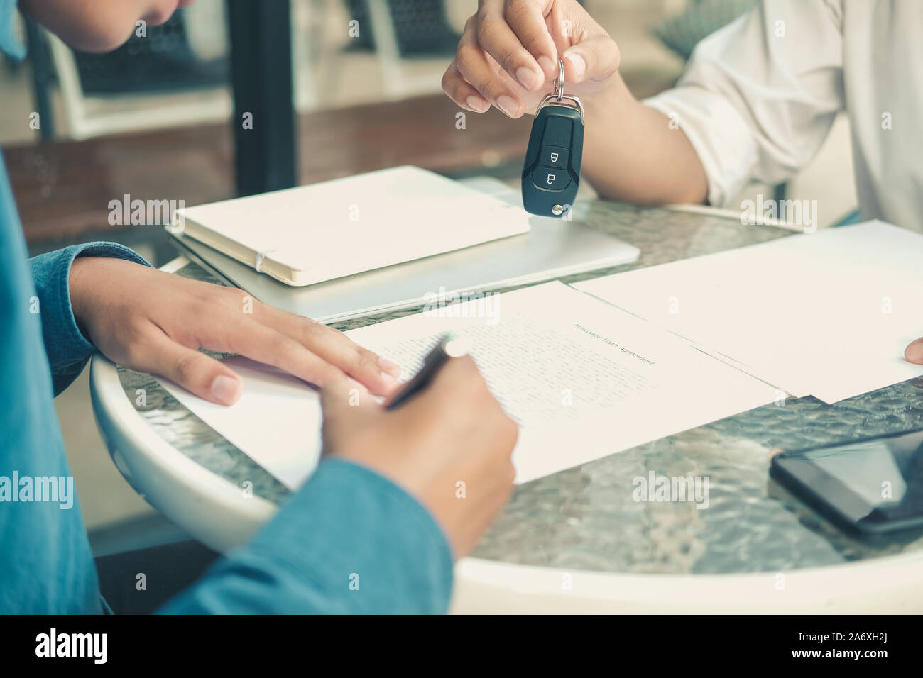 Dealer Salesman Giving Car Key To New Owner Client Signing