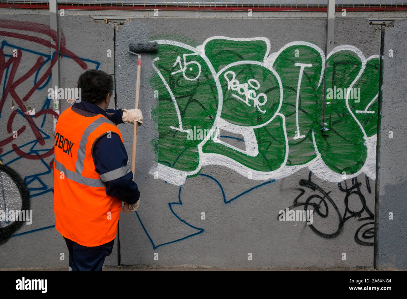 an employee of the municipal service removes graffiti from the wall in Moscow city, Russia Stock Photo