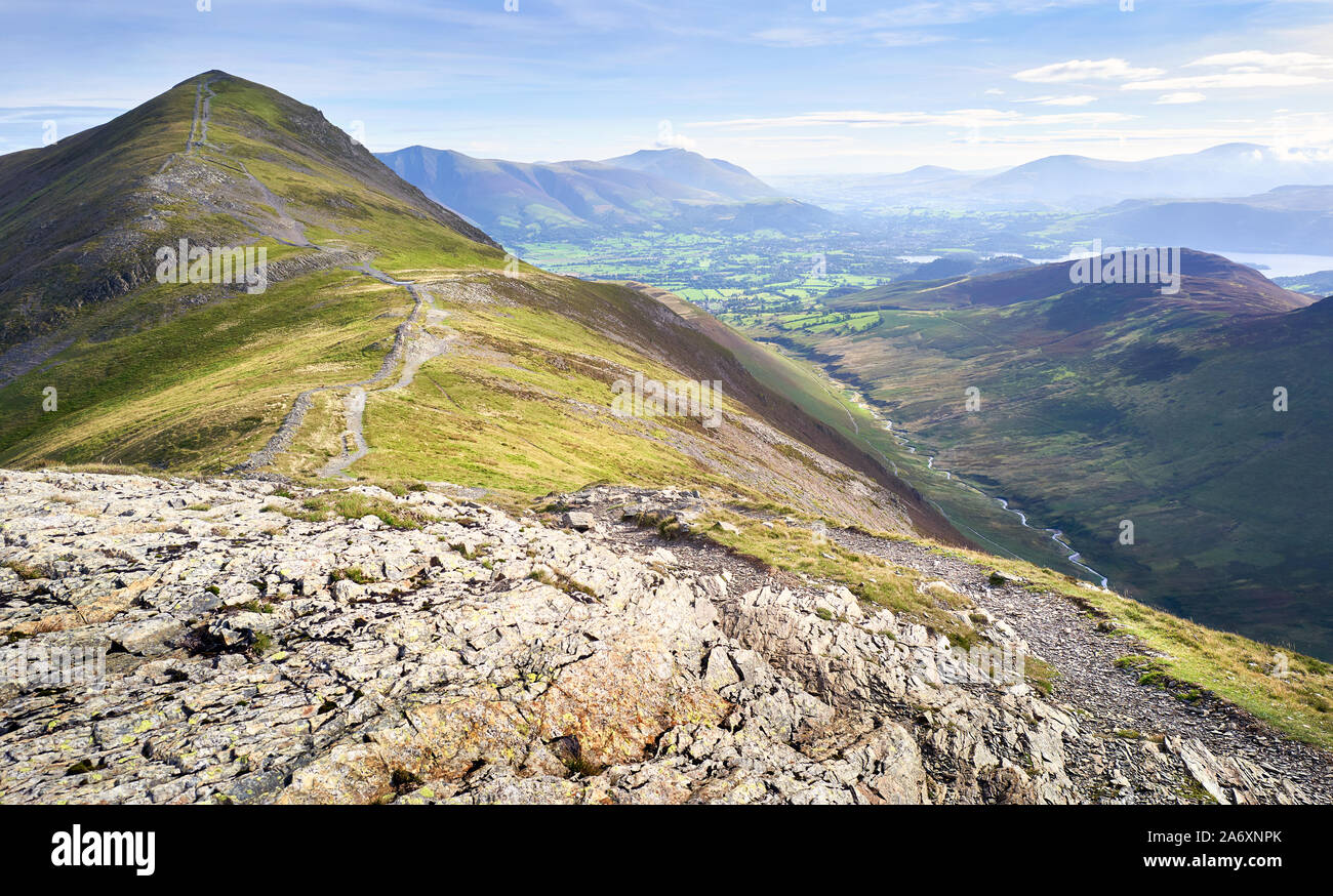 The rugged path from the summit of Hobcarton with Grisedale Pike in the distance and the valley of Coledale Beck far below, the Lake District, England Stock Photo