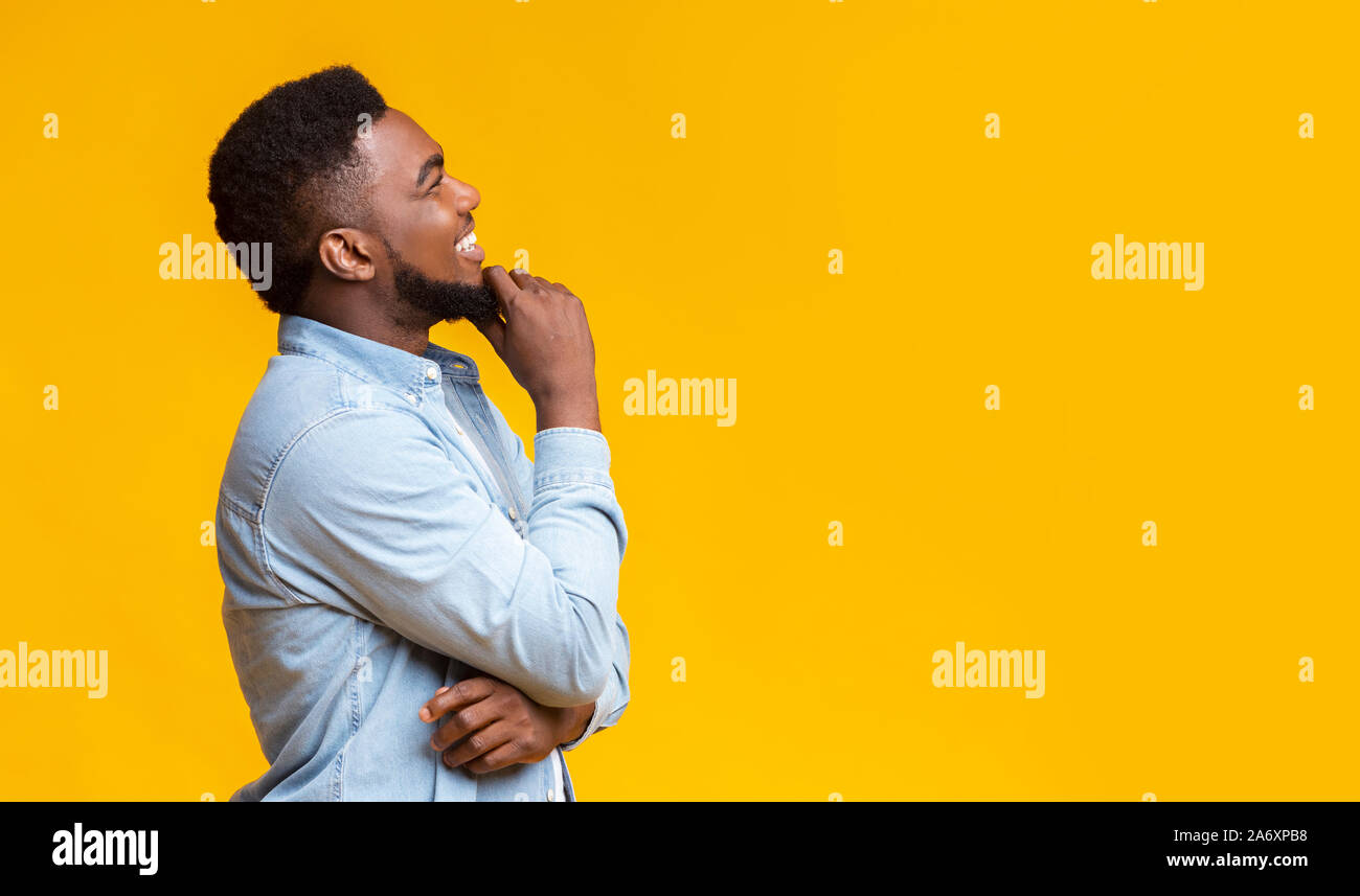 Profile portrait of smiling black guy touching his beard Stock Photo