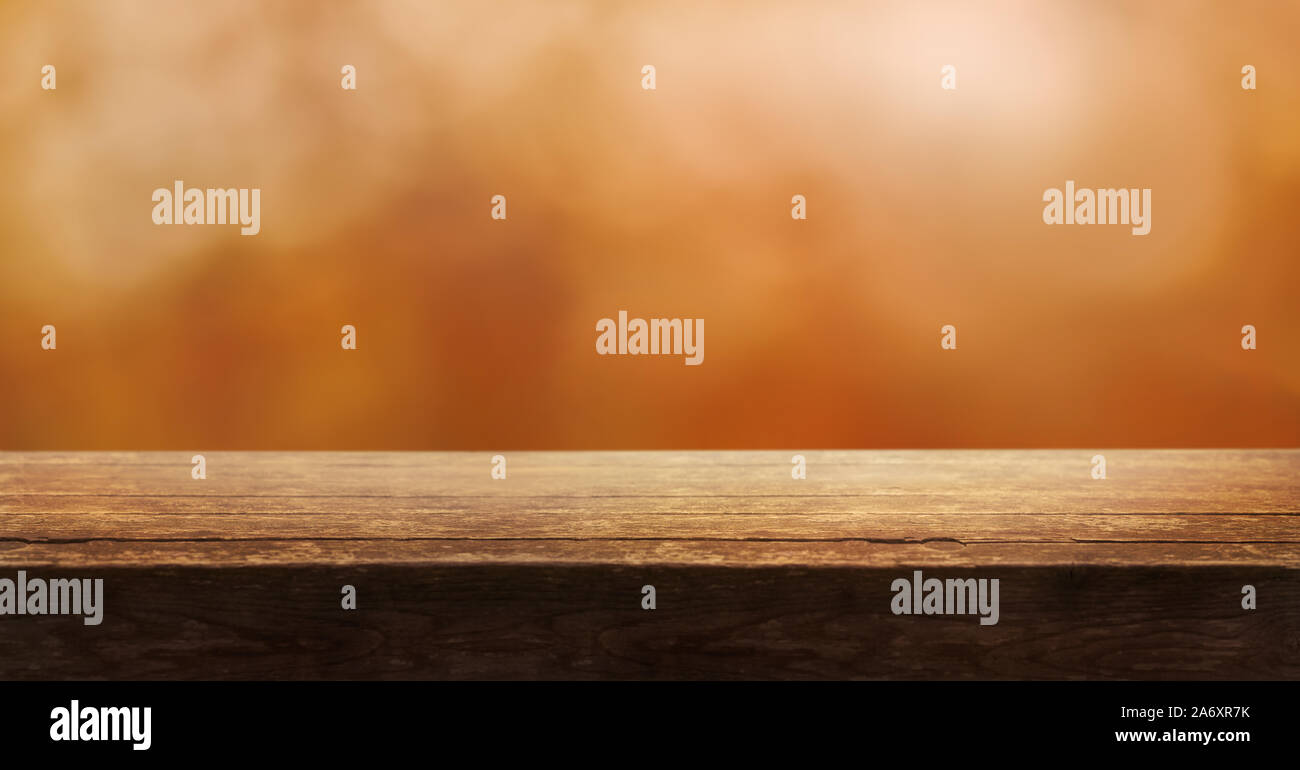 A wooden table top product display with a blurred background scene of blurred foliage at sunset. Stock Photo