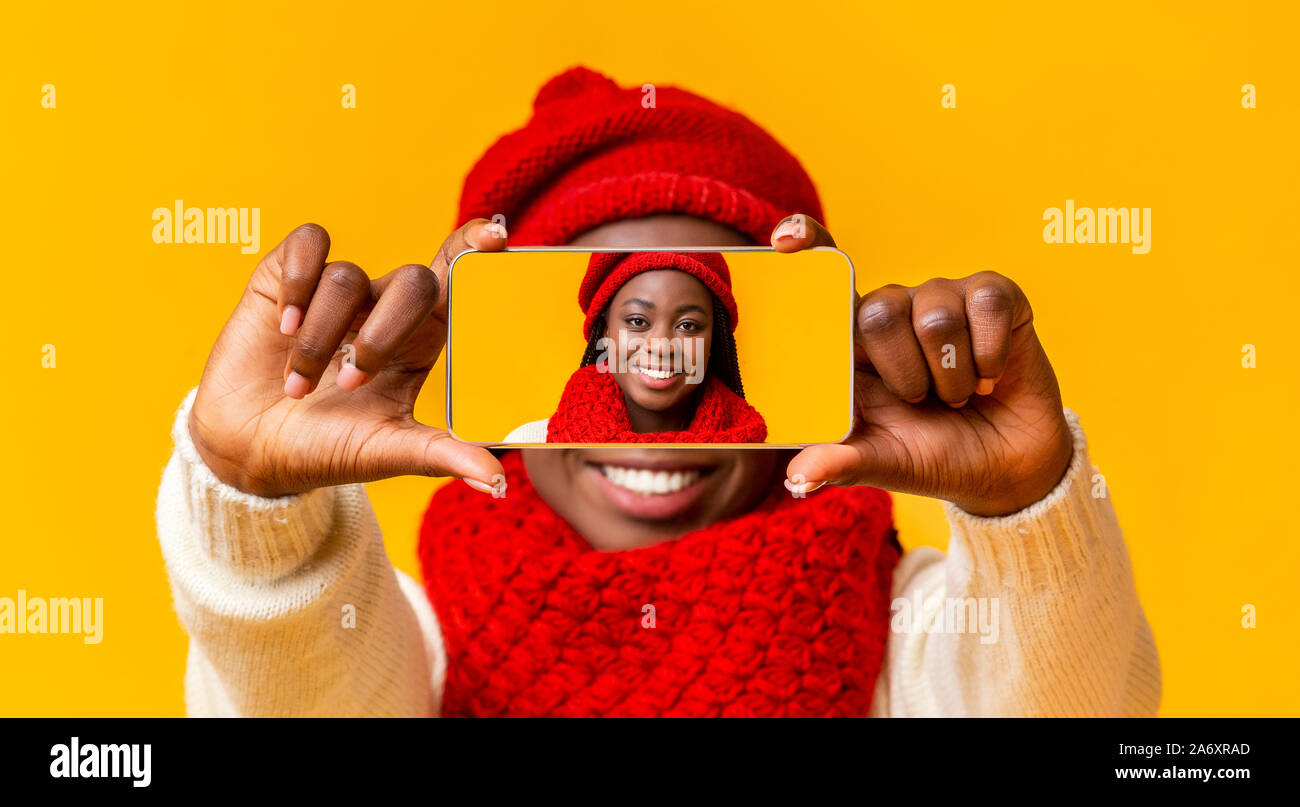 Portrait of happy afro girl covering her face with smartphone Stock Photo