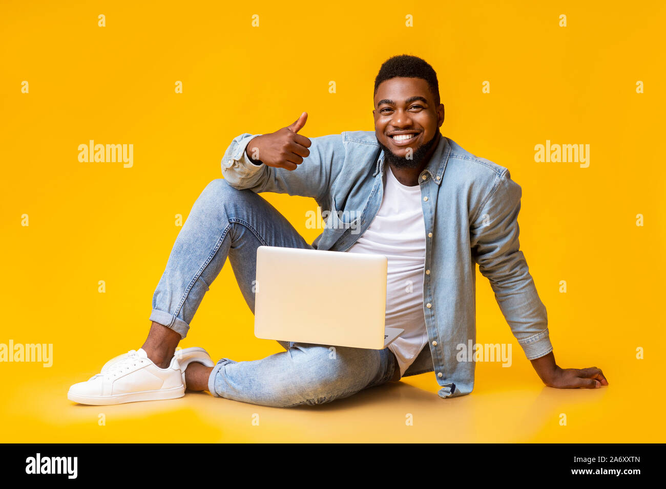 Happy black guy sitting with laptop and showing thumb up Stock Photo - Alamy