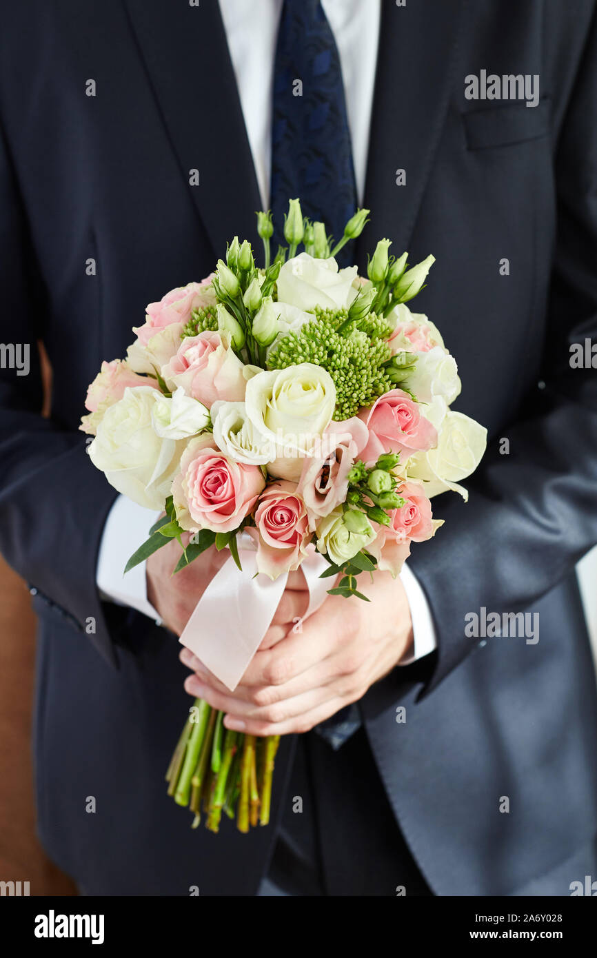 Man groom holds the Bridal bouquet. The groom meets the bride with a