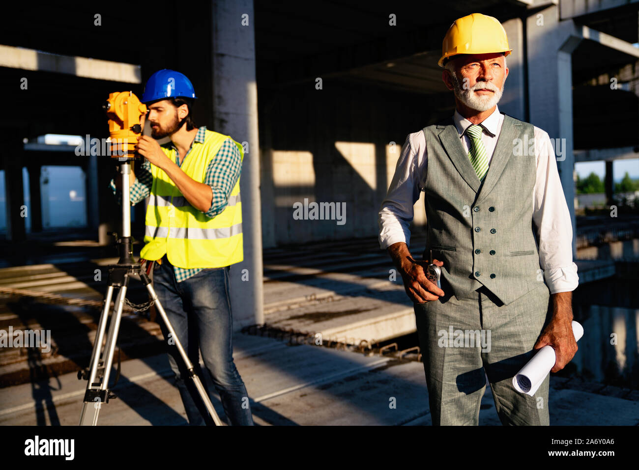Two satisfied engineers talking at building site with construction structure in background Stock Photo