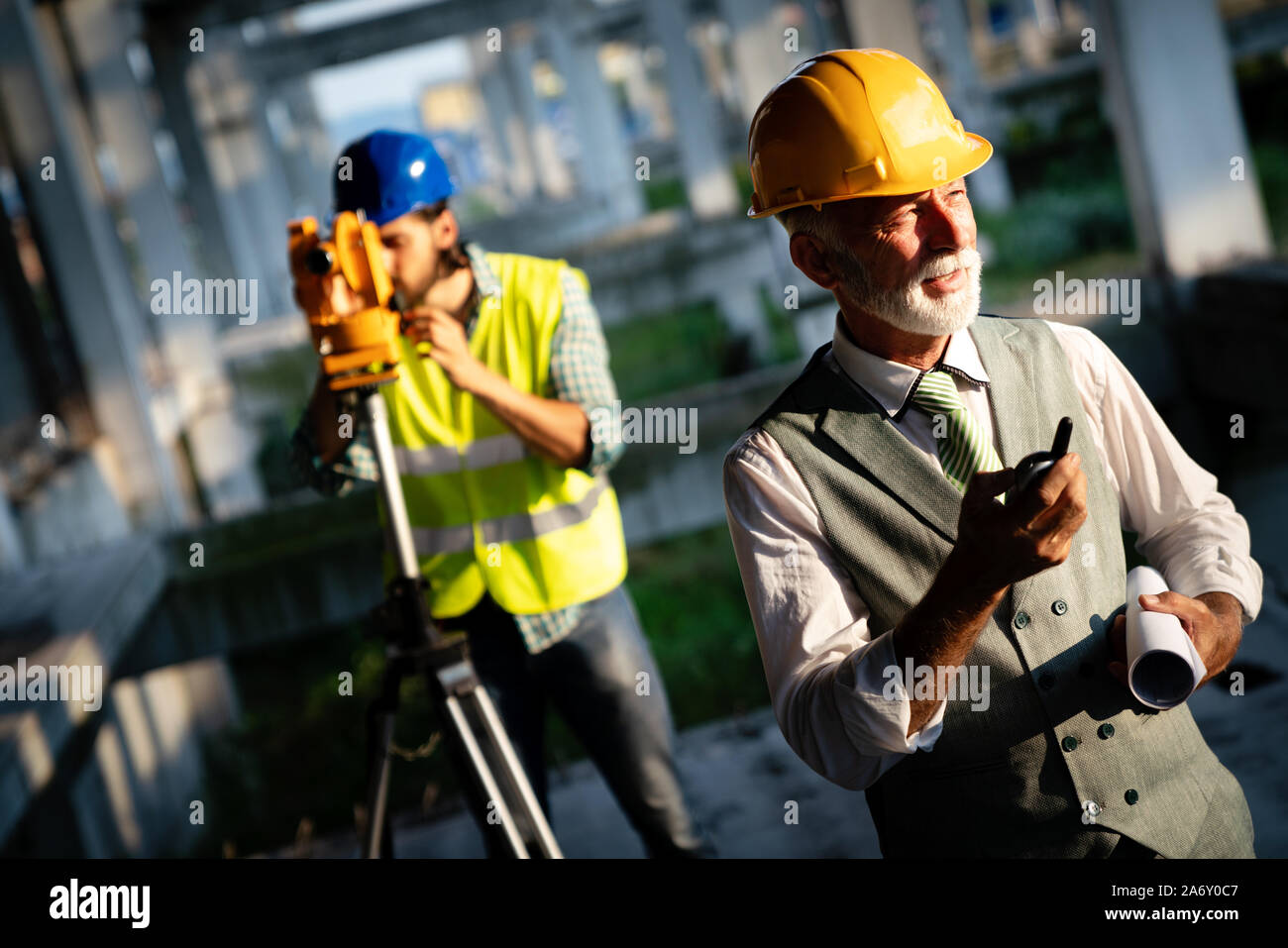 Two satisfied engineers talking at building site with construction structure in background Stock Photo