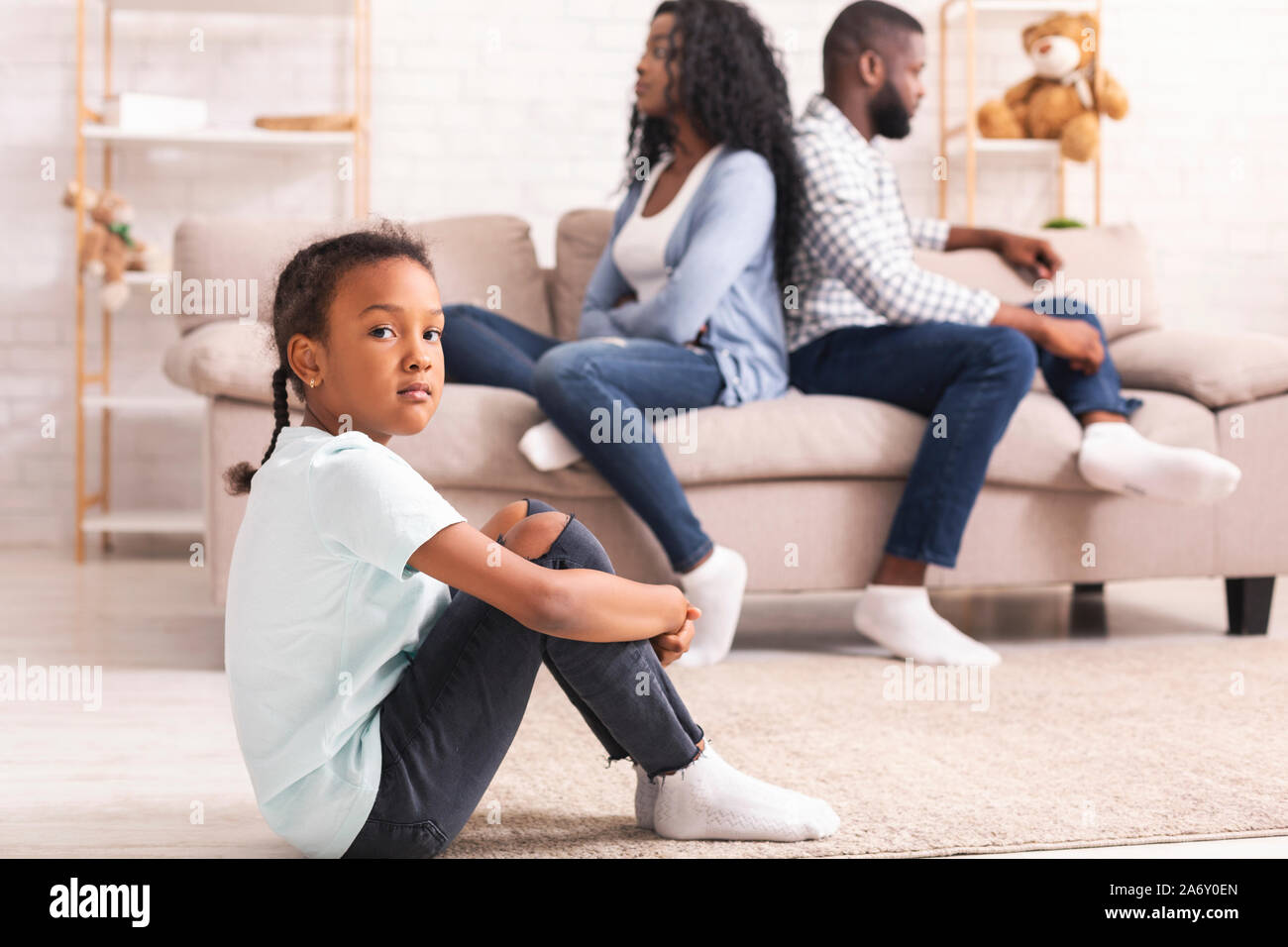 Upset black girl sitting separately from parents after their arguing Stock Photo