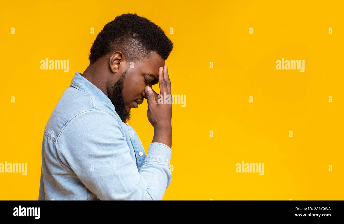 Profile portrait of depressed black guy touching his forehead Stock Photo