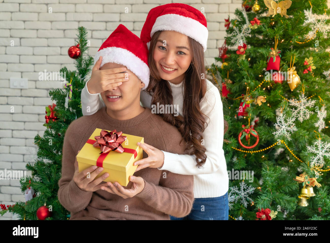 beautiful asian girl give surprise christmas gift to her boyfriend in Christmas holiday season greeting. Stock Photo