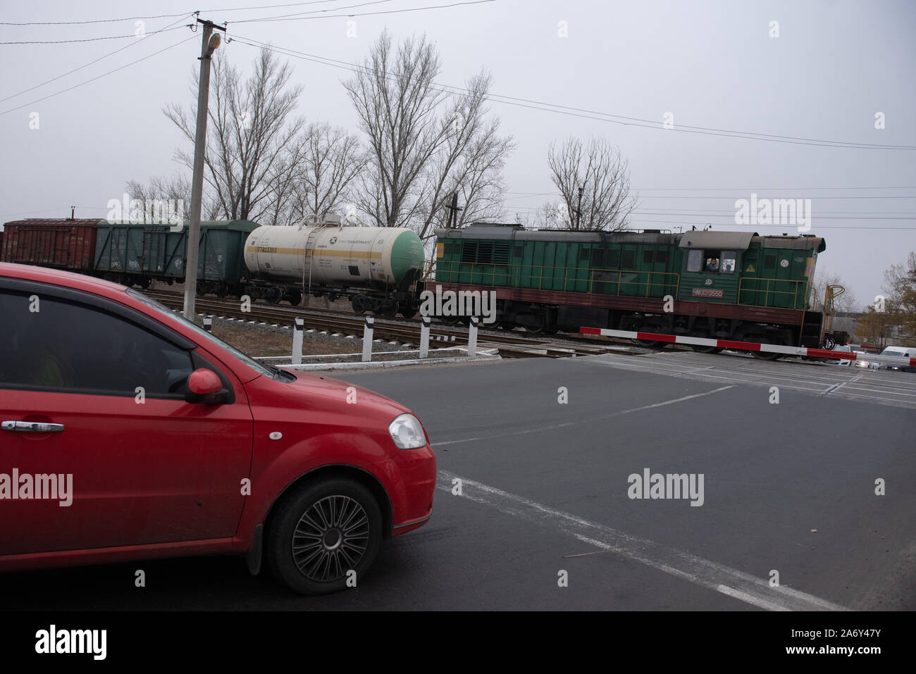 A cargo train drives by an interception as cars wait to pass Stock