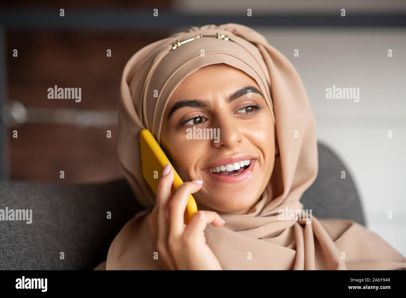Smiling Muslim girl talking on the phone with boyfriend Stock Photo