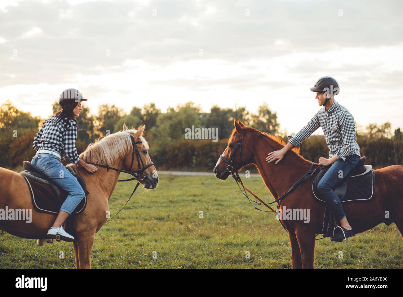 Happy loving couple spending time with horses on ranch Stock Photo