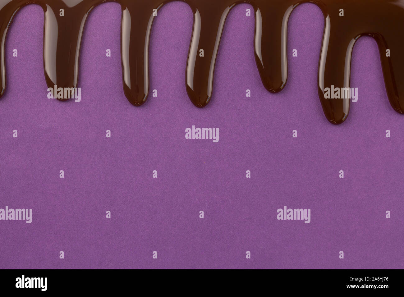 Chocolate dripping down from top of purple background with space for text at bottom of  purple birthday celebration background Stock Photo