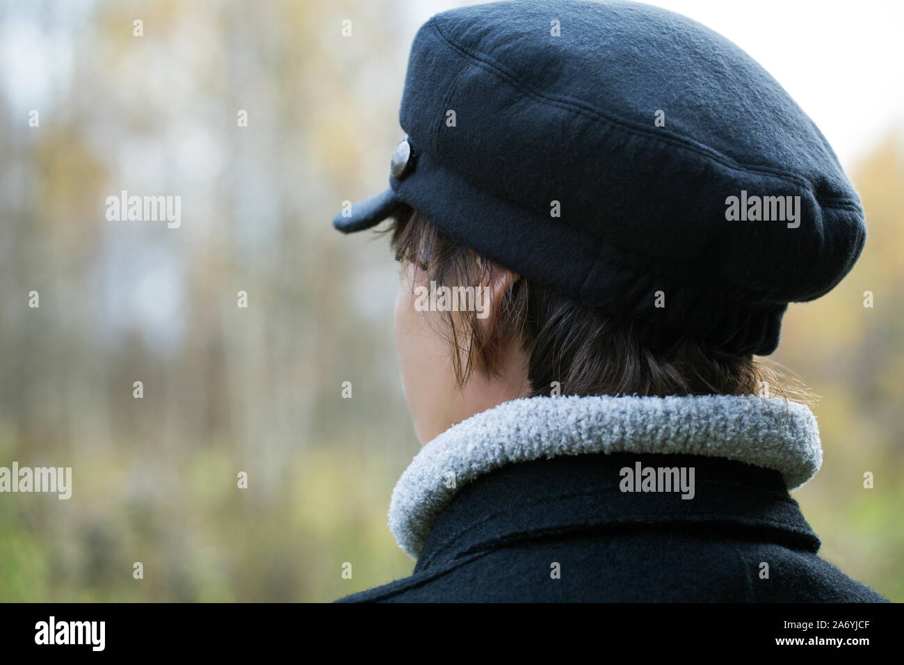 middle-aged woman in a jacket looks at the forest in the autumn day Stock Photo