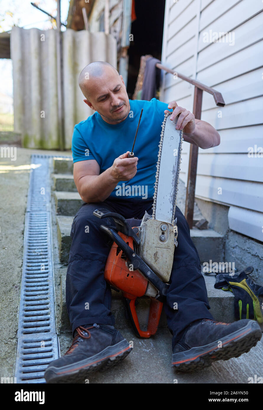Lumberjack sharpening and tightening chain on his chainsaw Stock Photo