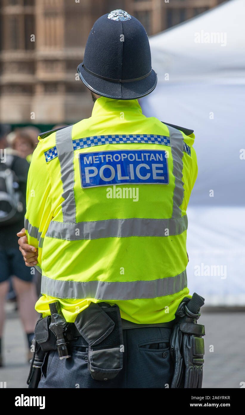 Police officer with his back to camera, stands watch nearby to the Climate Change demonstration organisers tent, by the House of Parliament, London. Stock Photo
