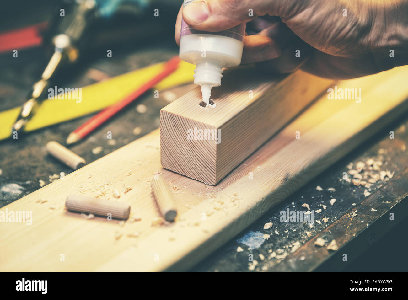 joinery - joiner put the glue into a drilled hole for wooden dowel joint Stock Photo