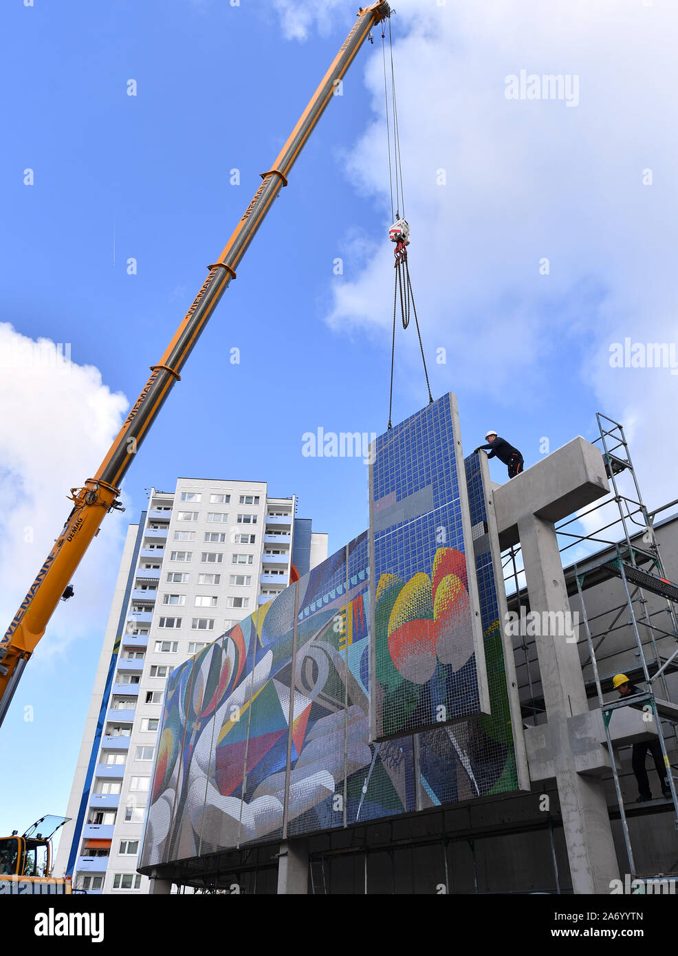 Erfurt, Germany. 29th Oct, 2019. An element of the wall mosaic 'The relationship of man to nature and technology' (1980-1984) by the Spaniard Josep Renau (1907-1982) is mounted. After four years of planning and restoration, the large mosaic returns. The mural was saved from destruction in 2012 before the demolition of the cultural and leisure centre on Moskauer Platz. It was professionally removed and stored in containers until its restoration. Credit: Martin Schutt/dpa-Zentralbild/dpa/Alamy Live News Stock Photo