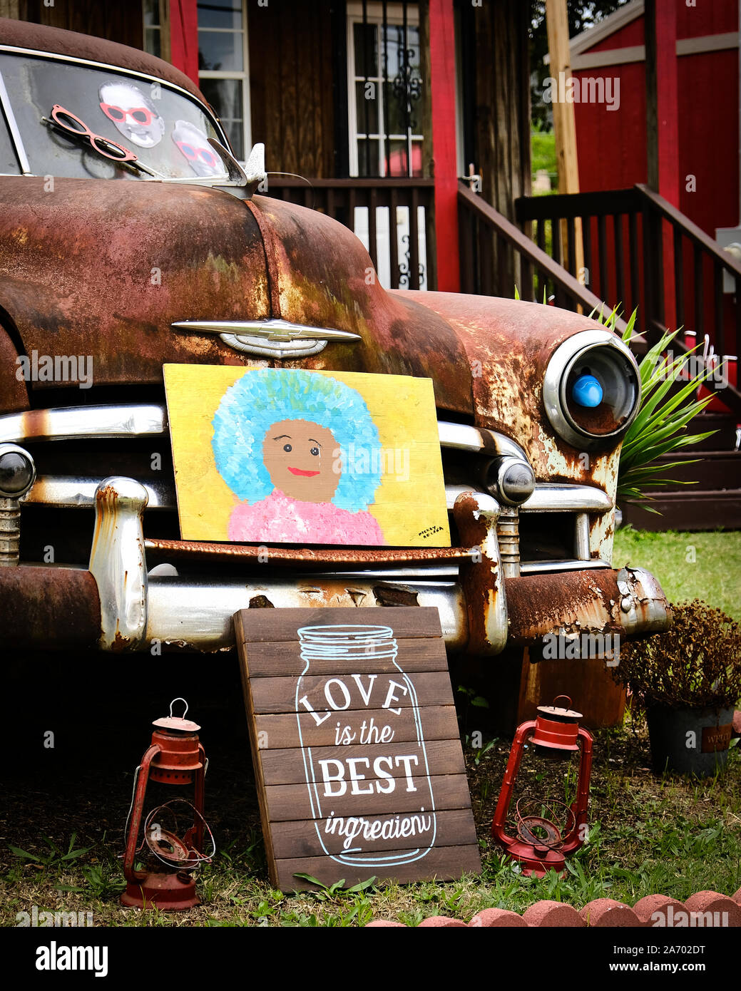 Yard art with an old rusty car, hand made sign and painting in the front yard in a residential setting in Montgomery Alabama, USA. Stock Photo