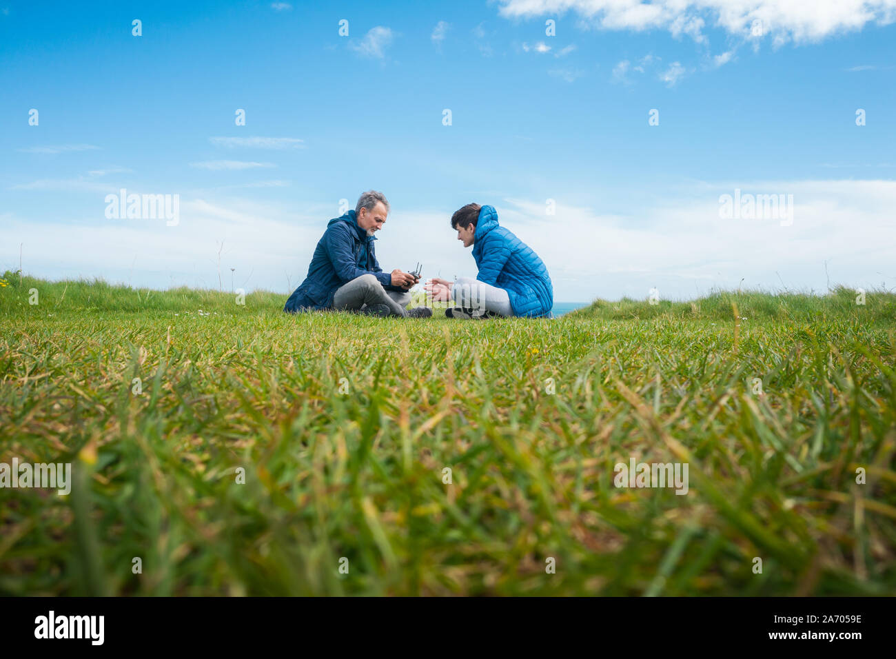 Father and son sitting on the grass and flying drone Stock Photo - Alamy