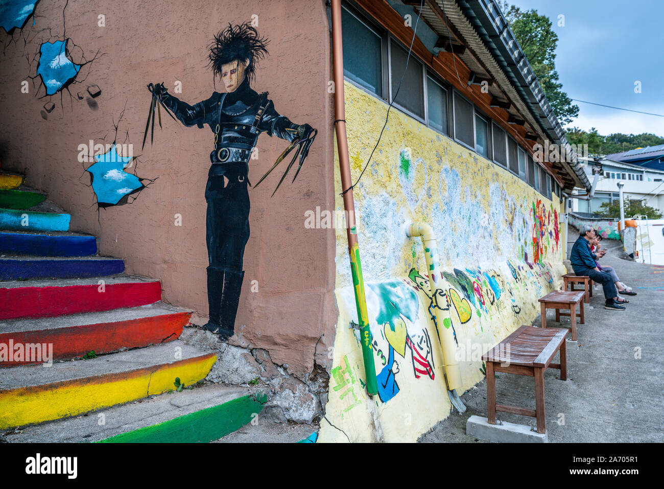 Jeonju Korea , 6 October 2019 : Jaman mural village with colourful murals and people sitting on a bench in Jeonju South Korea Stock Photo