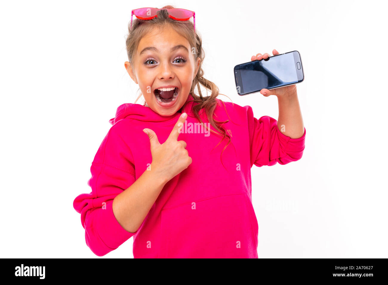 naughty girl in a pink hoodie on a white isolated background gestures to a smartphone Stock Photo