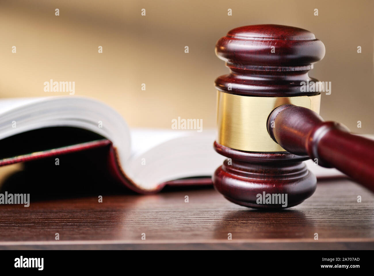 Judges wooden gavel with a brass band around the mallet standing upright on a wooden counter top alongside a law book conceptual of judgements and law Stock Photo