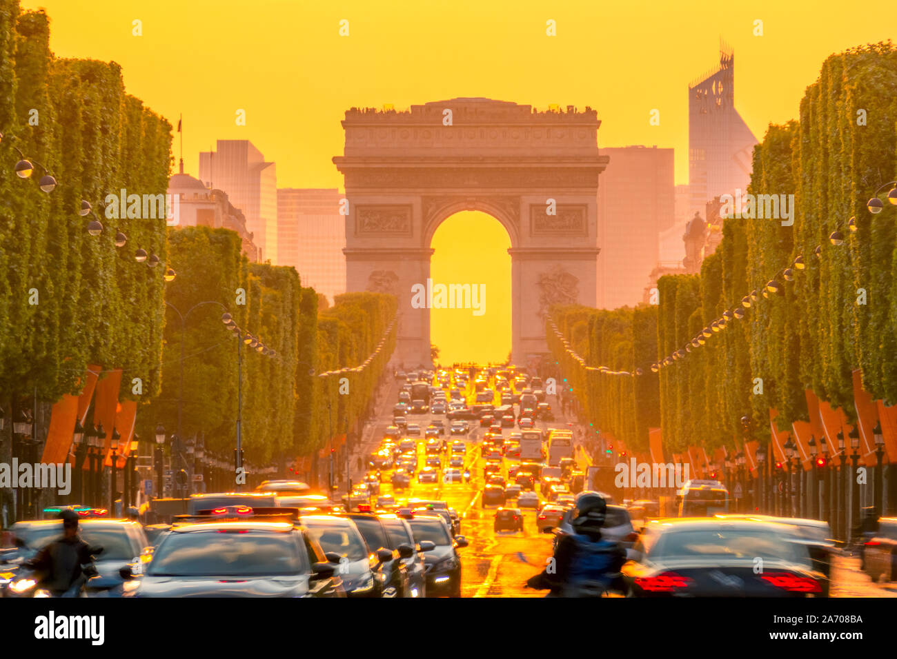 France. Paris. Dense traffic on the Champs Elysees. Triumphal Arch on a background of orange sunset Stock Photo
