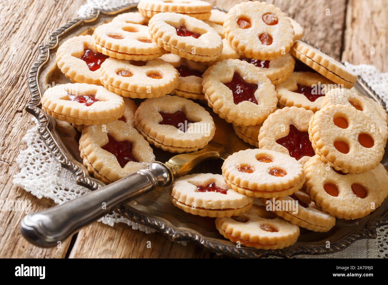 Traditional Austrian christmas cookies - Linzer biscuits filled with red strawberry and apricot jam close-up on the table. Horizontal Stock Photo
