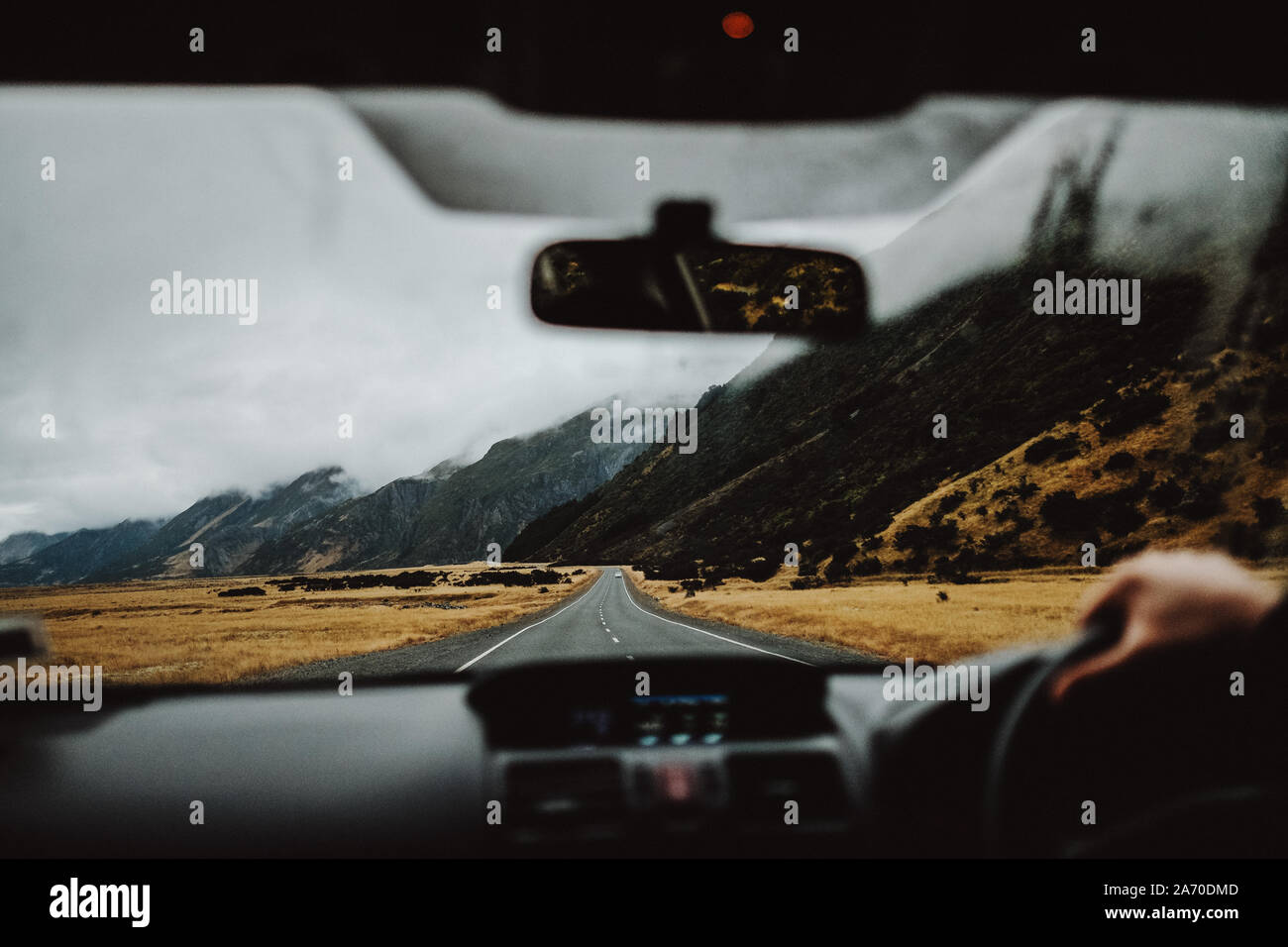 Driving a car in New Zealand with a mountain background in a moody day Stock Photo
