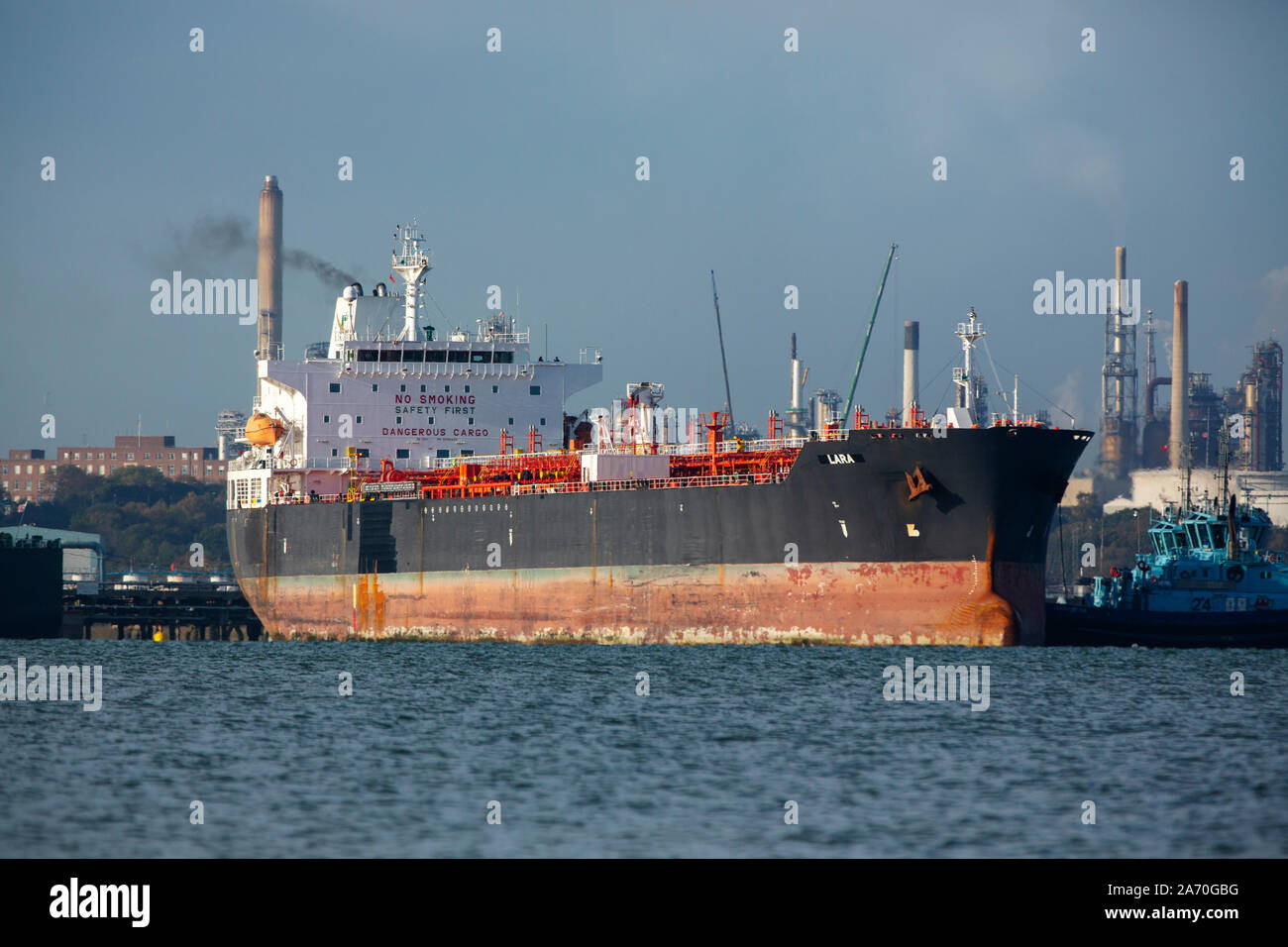 Supertanker Lara coming alongside Fawley oil refinery in Southampton water. Helped by tugs to enter the birth safely. Stock Photo
