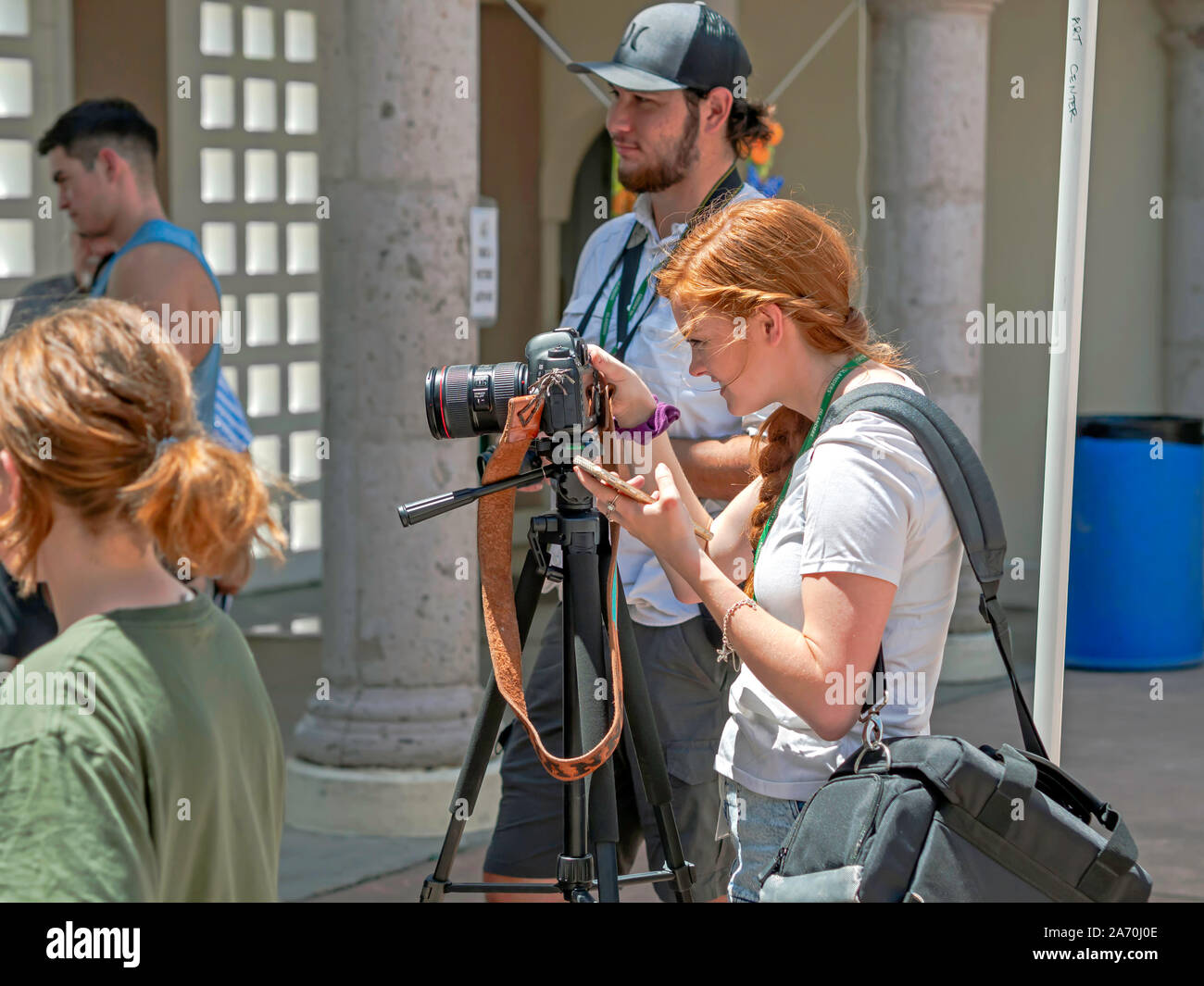 A young redhead Caucasian woman takes photographs with a tripod mounted camera at the Art Center of Corpus Christi. Arts Alive Festival 2019. Stock Photo