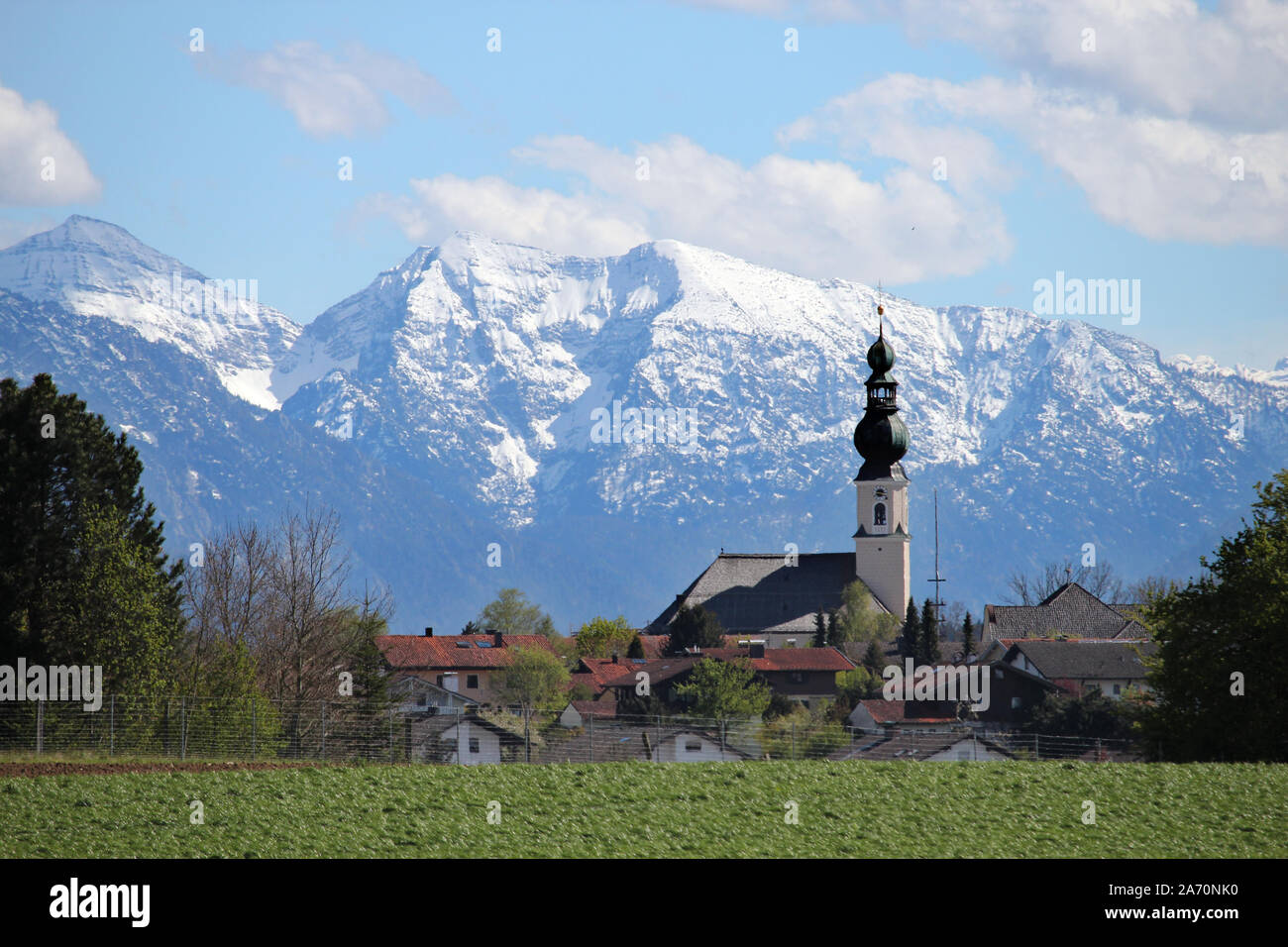 die Pfarrkirche von Traunwalchen scheint in diesem Telefoto ganz nah vor den Schneewänden der Chiemgauer Berge * Traunwalchen in front of the Alps Stock Photo