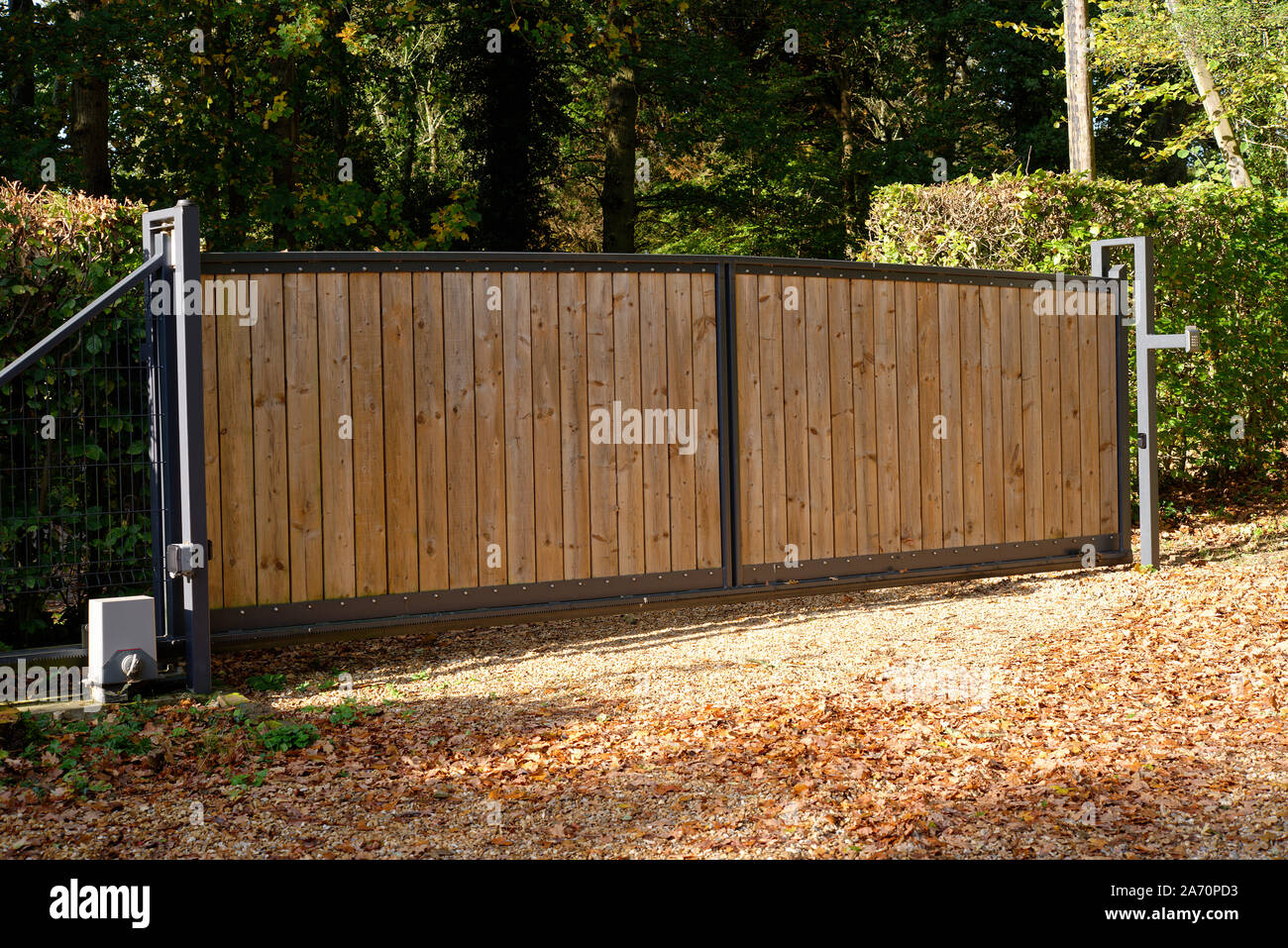 A sliding electric powered house gate. Security and privacy with a tall wood panelled steel framed gate. Stock Photo